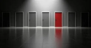 An image showing several doors, all gray except one is red