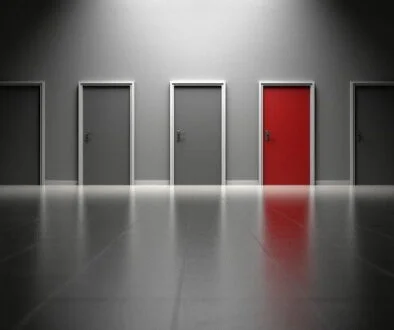 An image showing several doors, all gray except one is red